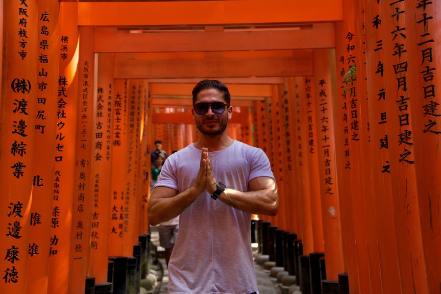 Nihat steht in den orangefarbenen Torii-Gaengen des Fushimi-Inari-Schreins in Kyoto.